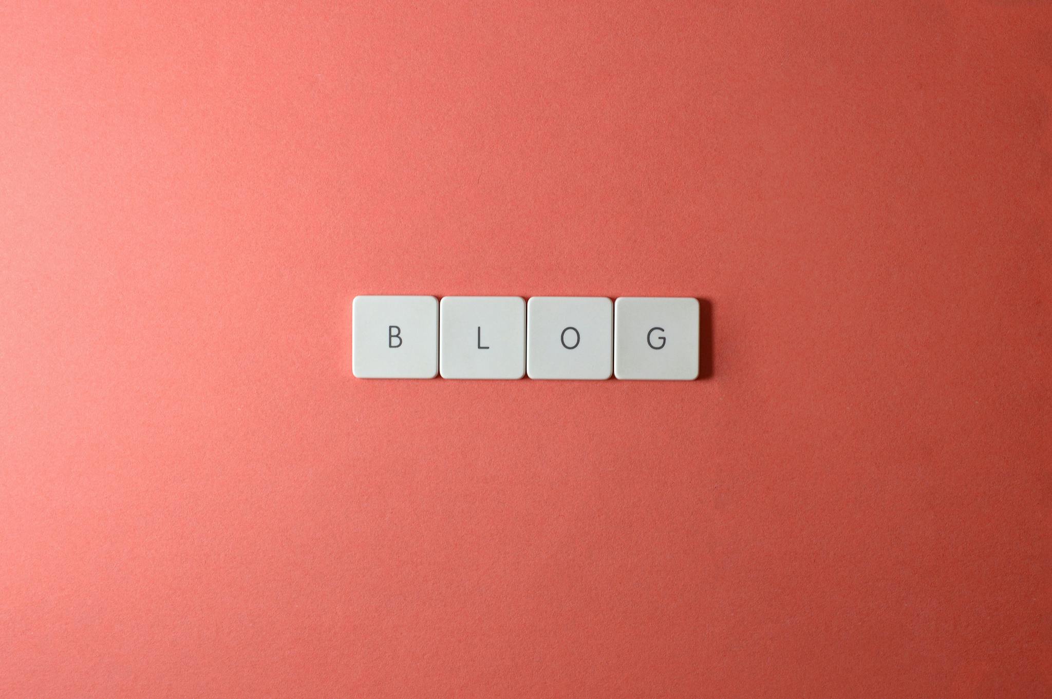 A minimalist image of keyboard keys spelling 'BLOG' on a coral background.