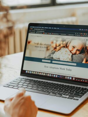 A woman researching adoption information on a laptop indoors.